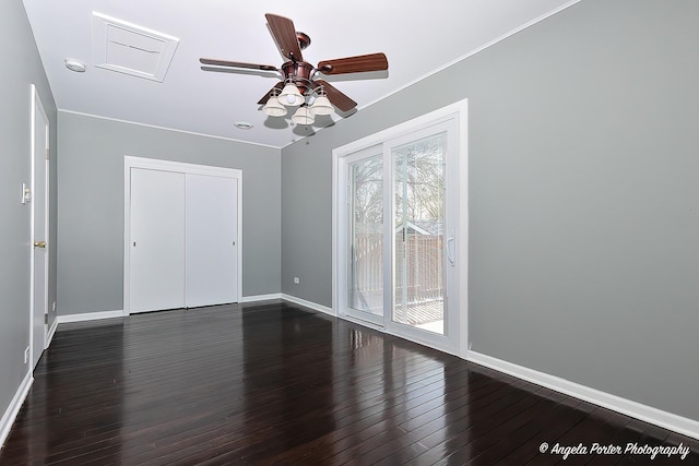 unfurnished bedroom with baseboards, attic access, dark wood-style floors, and access to exterior