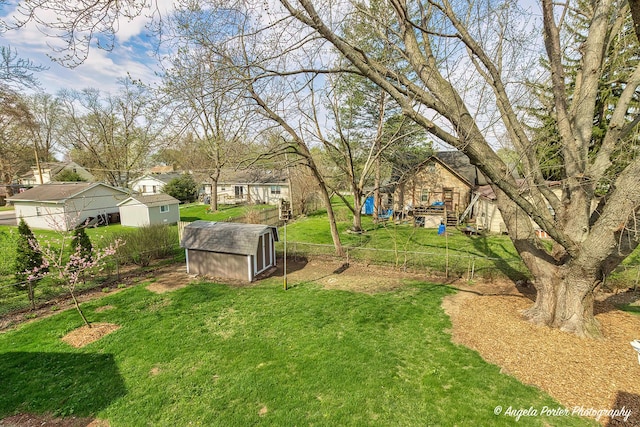 view of yard with an outdoor structure, a shed, a residential view, and fence