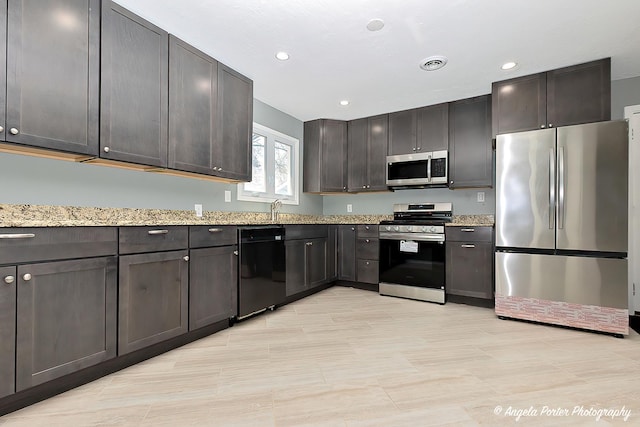 kitchen featuring visible vents, appliances with stainless steel finishes, light stone countertops, a sink, and recessed lighting