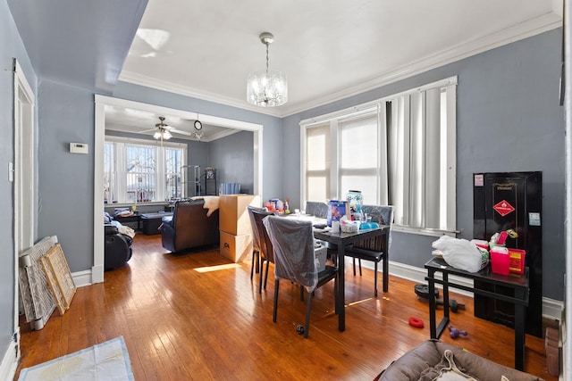 dining room with hardwood / wood-style flooring, baseboards, crown molding, and ceiling fan with notable chandelier