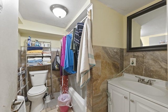 full bathroom featuring toilet, tile walls, wainscoting, tile patterned flooring, and vanity