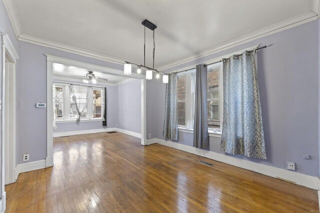 unfurnished dining area featuring wood-type flooring, baseboards, visible vents, and crown molding