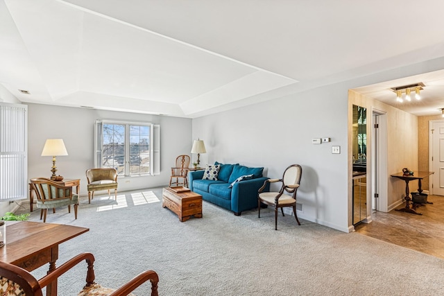 carpeted living room with baseboards and a tray ceiling