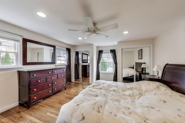 bedroom featuring light wood finished floors, baseboards, recessed lighting, a ceiling fan, and multiple closets