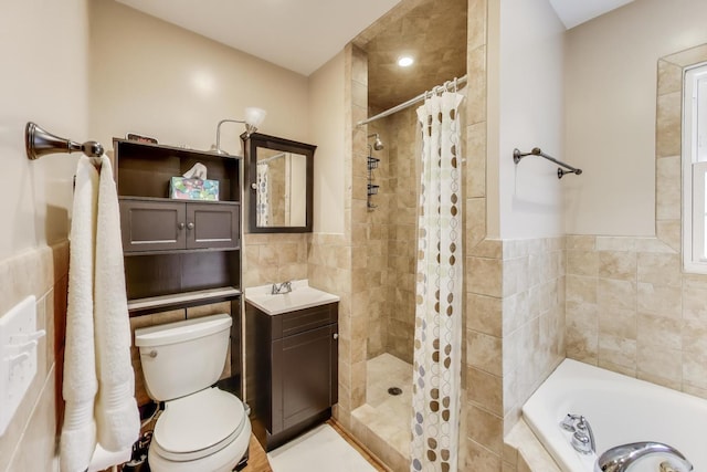 bathroom with a bath, vanity, tile walls, a tile shower, and toilet