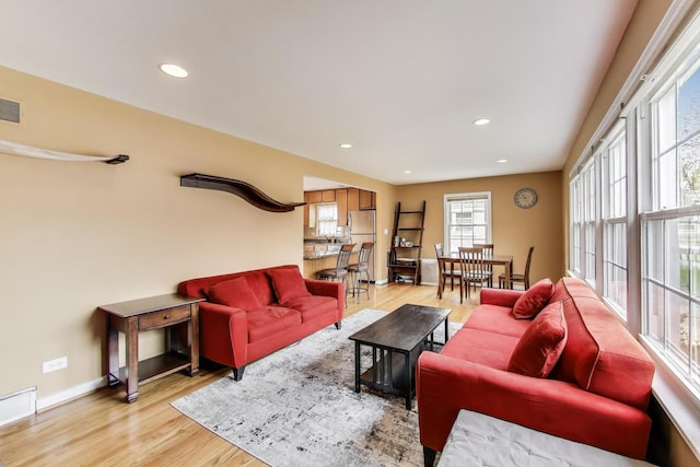 living room with visible vents, baseboards, recessed lighting, and light wood-style floors