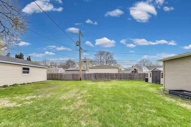 view of yard with an outdoor structure, fence, and a storage shed