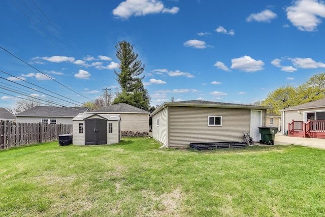 back of house with fence, a lawn, an outbuilding, and a storage shed
