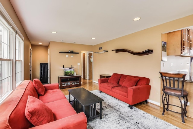 living room featuring visible vents, baseboards, wood finished floors, and recessed lighting