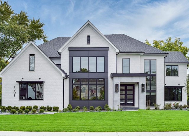 view of front of house featuring a shingled roof, brick siding, and a front yard