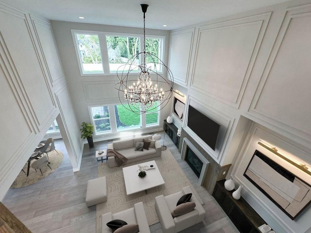 living room featuring a chandelier, wood finished floors, a decorative wall, and a fireplace with flush hearth
