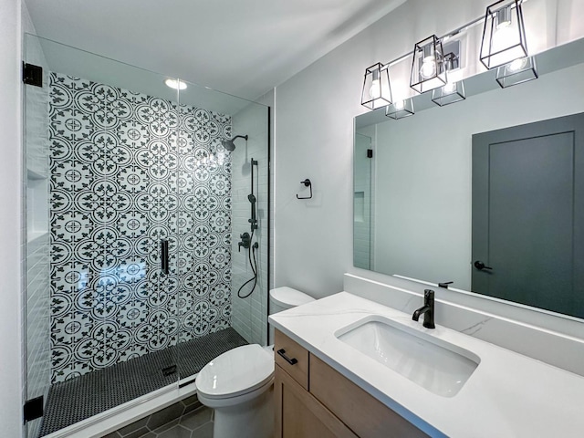 bathroom with tile patterned flooring, a tile shower, toilet, and vanity