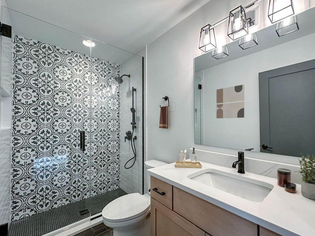 bathroom featuring a tile shower, toilet, and vanity