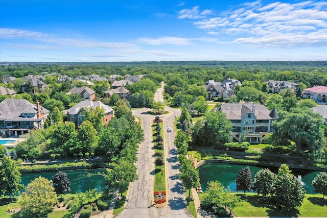 drone / aerial view featuring a view of trees, a residential view, and a water view