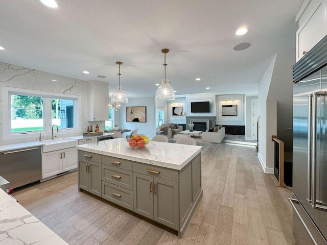 kitchen featuring light wood-style floors, appliances with stainless steel finishes, gray cabinets, and a sink