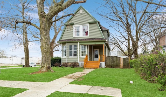 view of front of home featuring fence, a gambrel roof, a front lawn, and roof with shingles