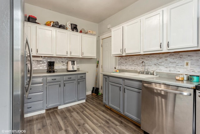 kitchen featuring decorative backsplash, stainless steel appliances, a sink, and gray cabinets