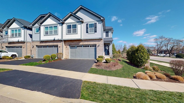 townhome / multi-family property with a garage, brick siding, and aphalt driveway