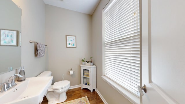 bathroom featuring baseboards, wood finished floors, a sink, and toilet