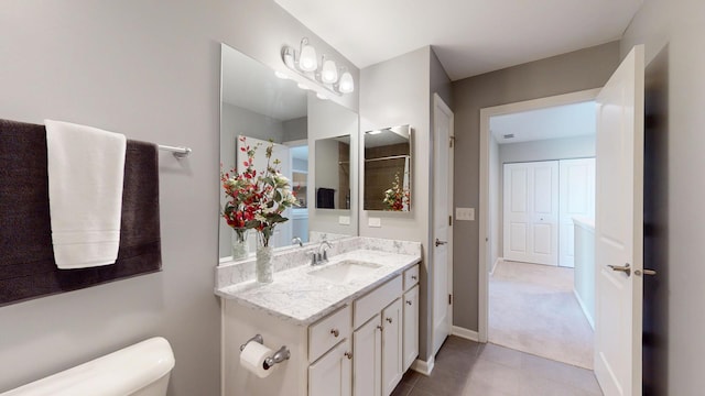 bathroom with tile patterned flooring, baseboards, toilet, and vanity
