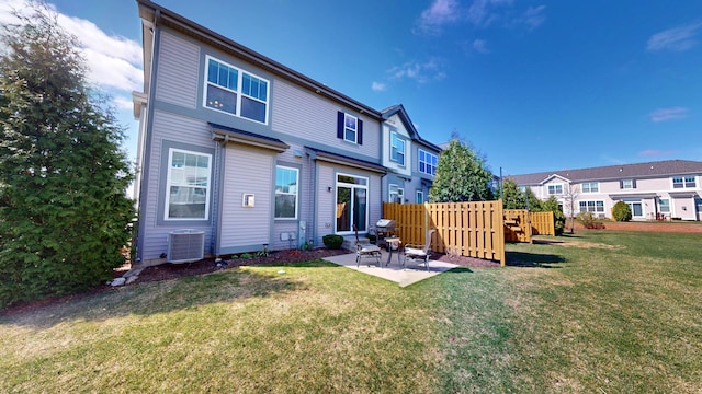 rear view of property featuring fence, a lawn, central air condition unit, and a patio