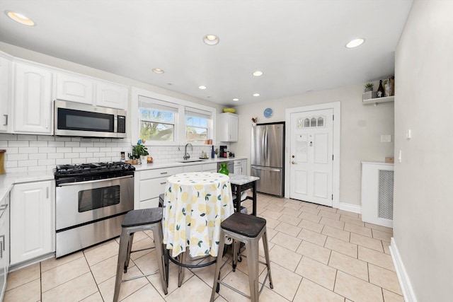 kitchen with light countertops, white cabinetry, appliances with stainless steel finishes, and decorative backsplash
