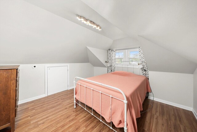 bedroom featuring baseboards, vaulted ceiling, and wood finished floors