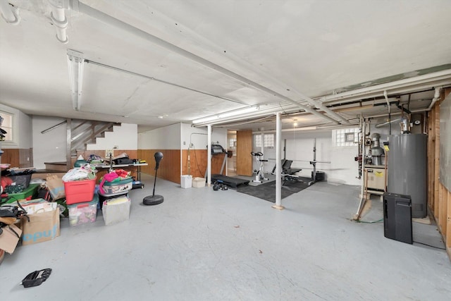 below grade area featuring stairs, wood walls, and gas water heater