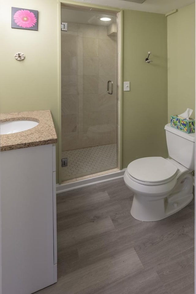 full bath featuring wood finished floors, toilet, a shower stall, and vanity