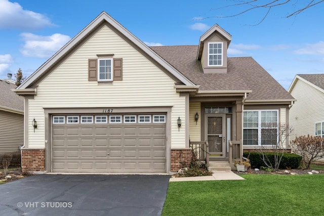 view of front of home featuring brick siding, driveway, a front yard, and a garage