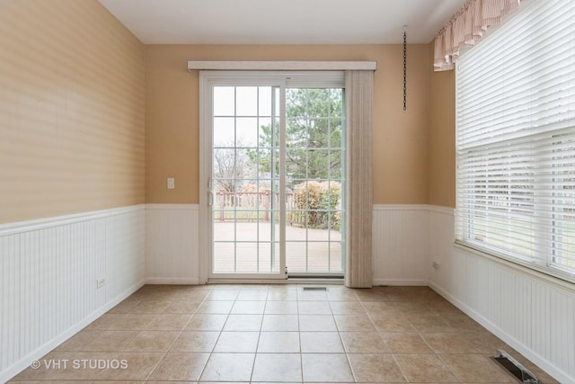 entryway featuring visible vents, a wainscoted wall, and light tile patterned floors