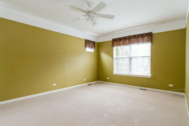 carpeted empty room with visible vents, a ceiling fan, and baseboards