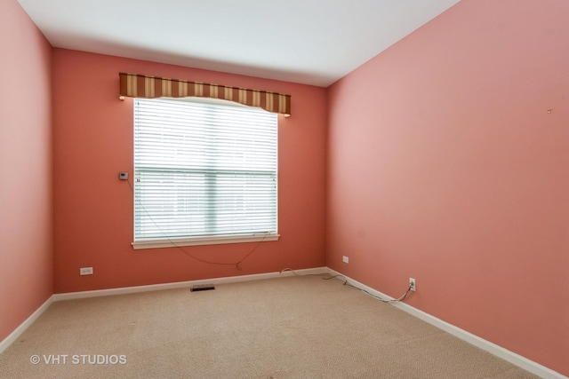 unfurnished room with carpet floors, visible vents, and baseboards