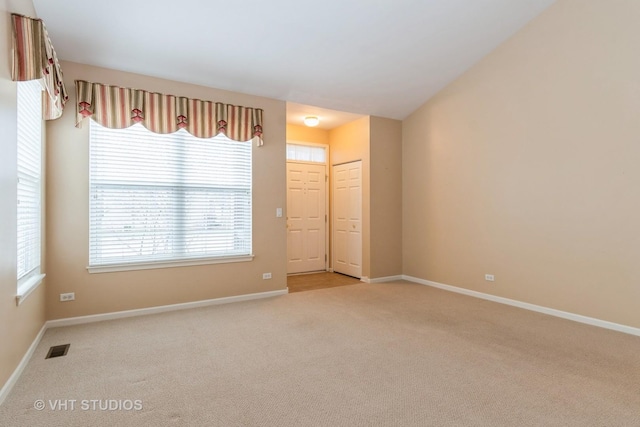 spare room with visible vents, baseboards, and light carpet