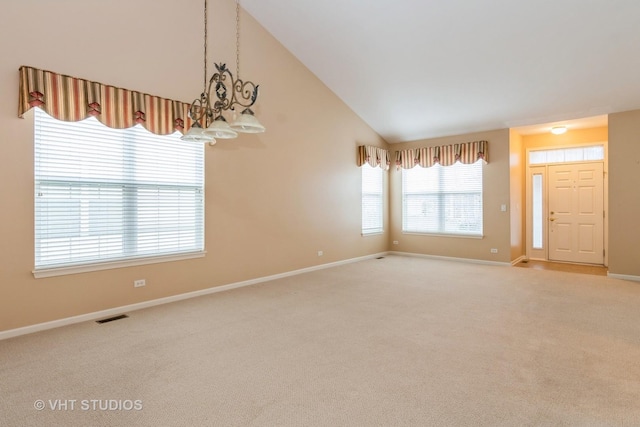 spare room with vaulted ceiling, visible vents, baseboards, and light carpet