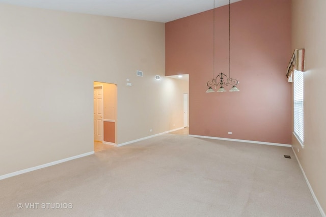 empty room with visible vents, baseboards, and high vaulted ceiling