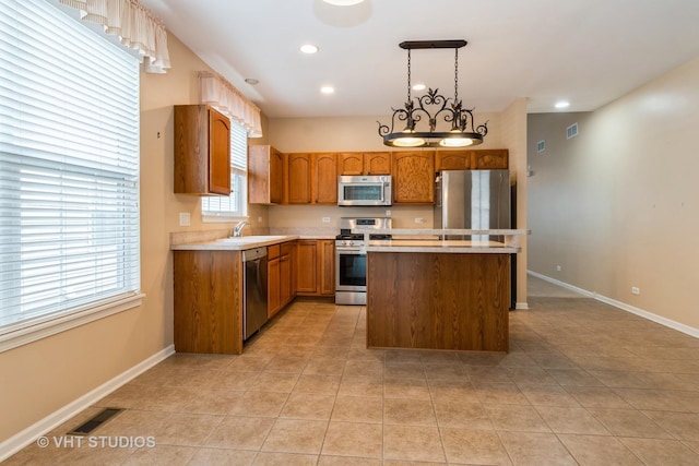 kitchen with stainless steel appliances, a center island, a sink, visible vents, and baseboards