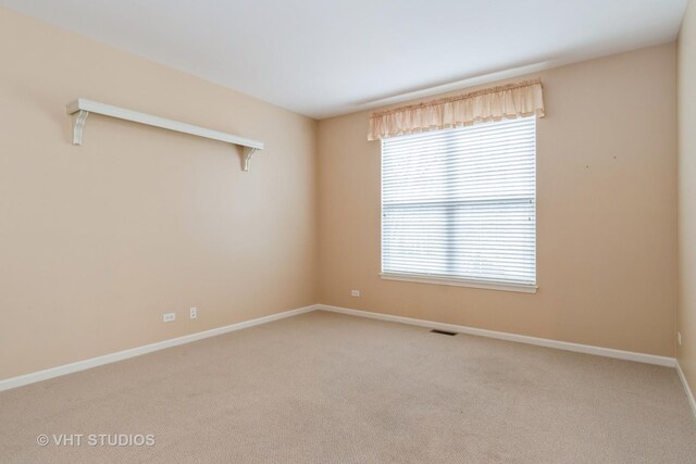 carpeted spare room featuring visible vents and baseboards