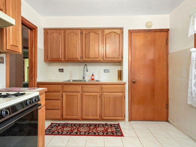 2758 N Newcastle Ave, Chicago, IL 60707 - kitchen with brown cabinetry, under cabinet range hood, a sink, and gas range