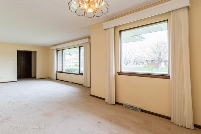 spare room featuring baseboards, light colored carpet, a chandelier, and visible vents