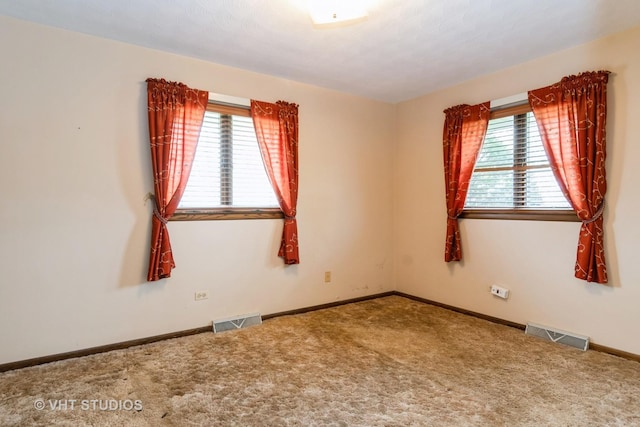 carpeted empty room featuring baseboards and visible vents