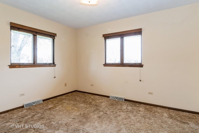 carpeted empty room featuring baseboards and visible vents
