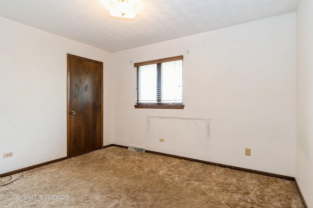 empty room with carpet floors, baseboards, and visible vents