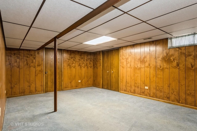 finished basement featuring visible vents, wood walls, a paneled ceiling, and carpet