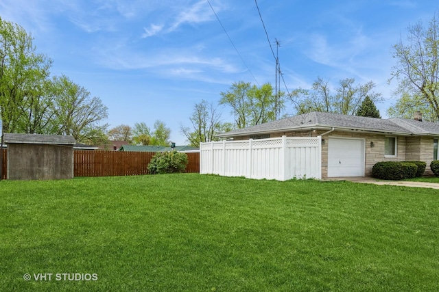 view of yard featuring an attached garage and fence