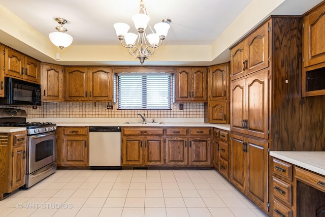 kitchen featuring a notable chandelier, a sink, light countertops, brown cabinetry, and stainless steel appliances