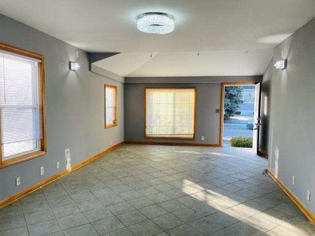 1218 Highland Ave, Joliet, IL 60435 - tiled spare room featuring vaulted ceiling, baseboards, and a healthy amount of sunlight