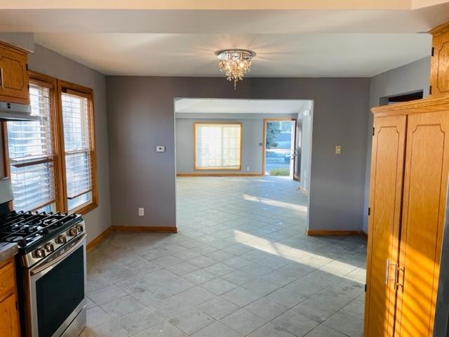 1218 Highland Ave, Joliet, IL 60435 - kitchen featuring a notable chandelier, baseboards, stainless steel range with gas stovetop, and a healthy amount of sunlight