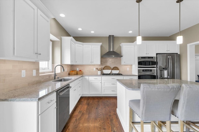 kitchen with dark wood finished floors, white cabinetry, a sink, stainless steel appliances, and wall chimney exhaust hood