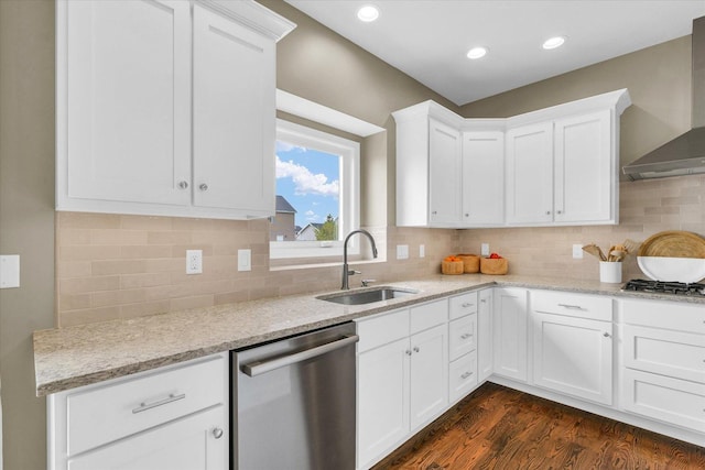 kitchen with wall chimney range hood, dark wood-type flooring, white cabinets, a sink, and stainless steel appliances